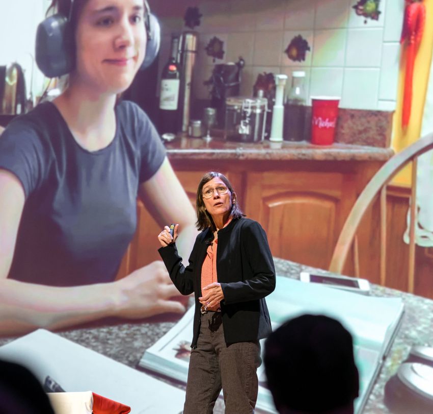 A presenter in front of a screen on a stage